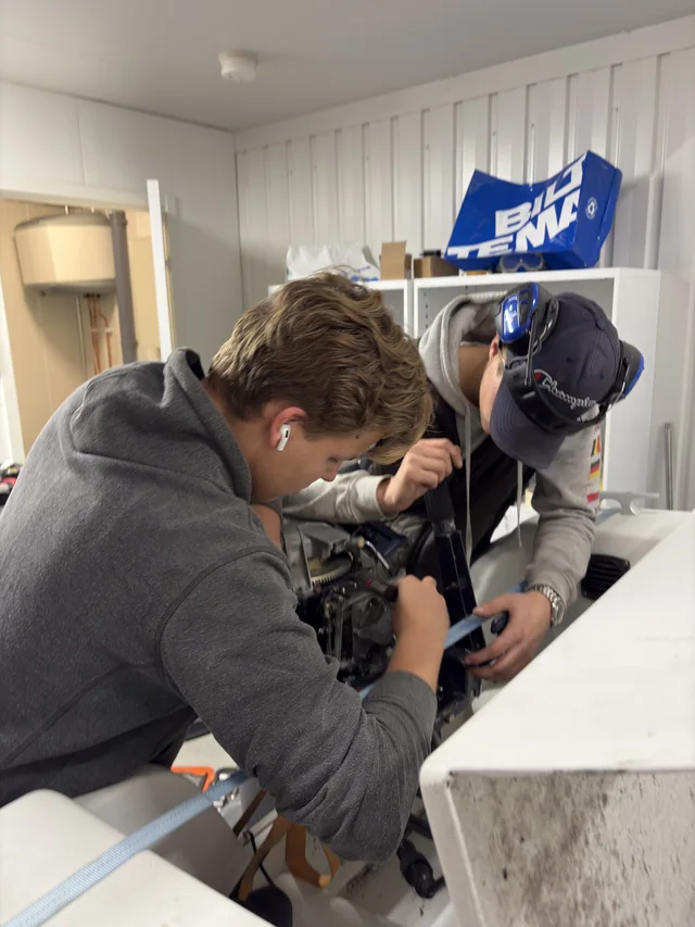 Två medarbetare arbetar med en båtmotor